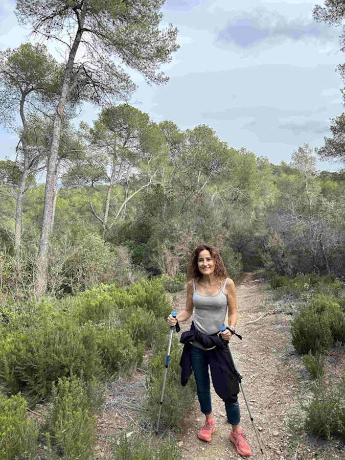 Maria Teresa Tacias Bueno, psicòleg Sant Cugat fent senderisme en un bosc amb dos pals