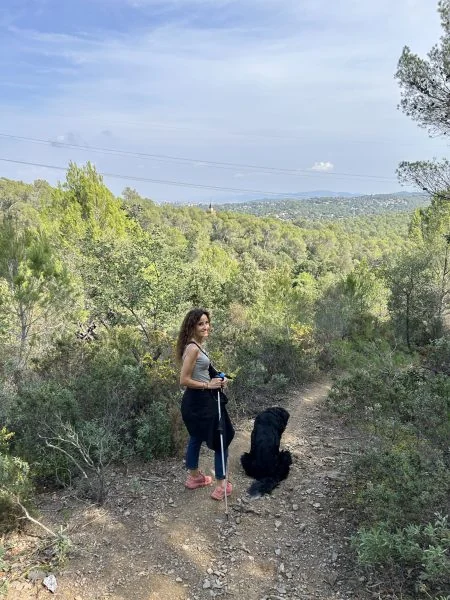 Maria Teresa, psicòleg Sant Cugat fent senderisme en un bosc amb dos pals i el seu gos